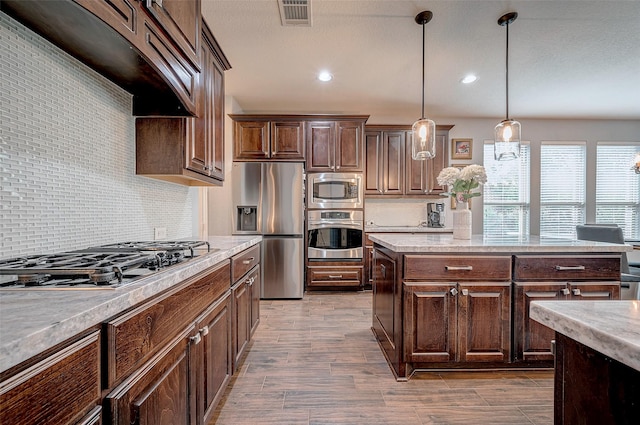 kitchen with stainless steel appliances, dark brown cabinetry, premium range hood, backsplash, and pendant lighting