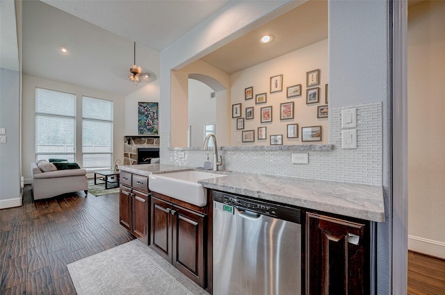 kitchen with dark brown cabinets, dishwasher, light stone counters, and sink