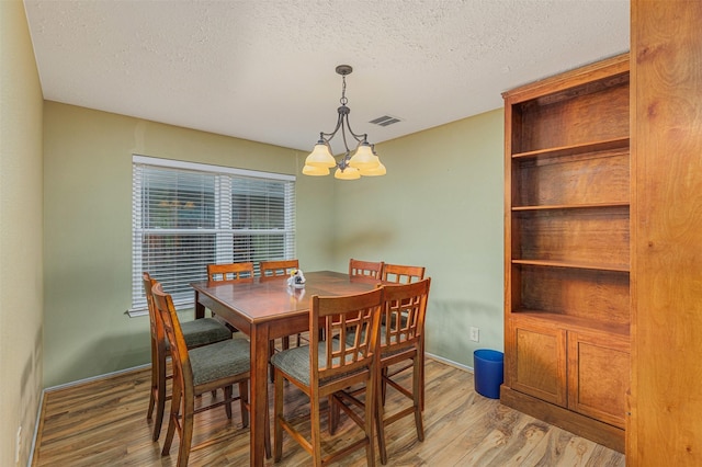 dining space featuring hardwood / wood-style flooring, a chandelier, and a textured ceiling