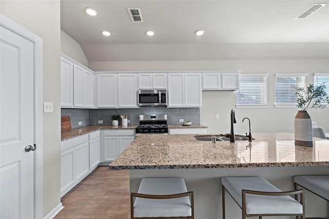 kitchen featuring stainless steel appliances, white cabinets, and stone counters