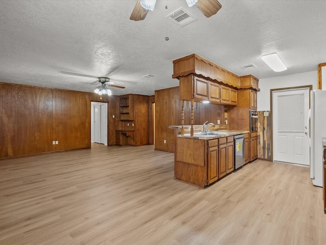 kitchen with stainless steel appliances, wooden walls, ceiling fan, and light hardwood / wood-style flooring