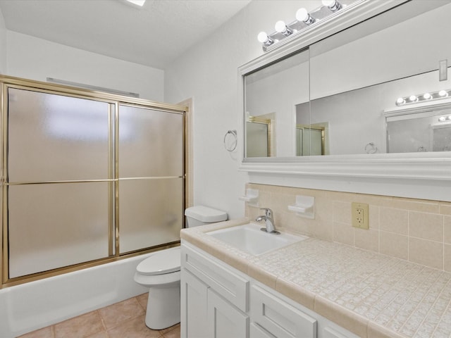 full bathroom with toilet, shower / bath combination with glass door, vanity, tile patterned flooring, and backsplash