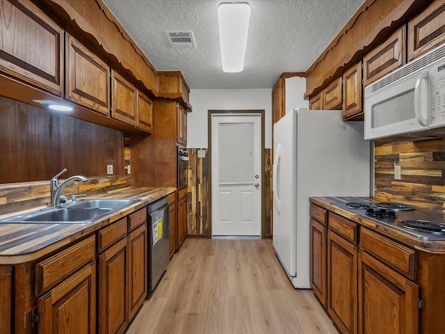 kitchen featuring stainless steel appliances, sink, a textured ceiling, and light wood-type flooring