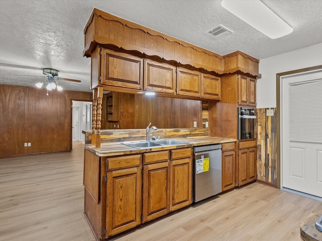 kitchen featuring sink, oven, stainless steel dishwasher, light hardwood / wood-style floors, and a textured ceiling