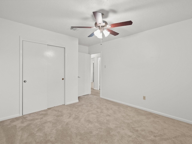 unfurnished bedroom with light colored carpet, a closet, and ceiling fan