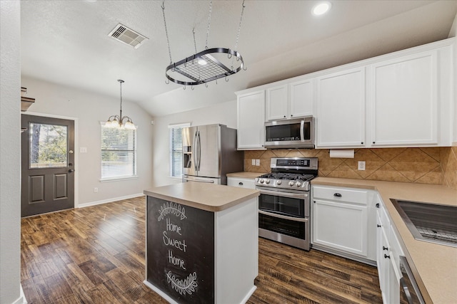 kitchen featuring dark wood-type flooring, hanging light fixtures, a kitchen island, stainless steel appliances, and white cabinets