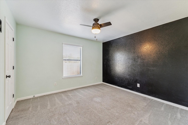 carpeted spare room featuring ceiling fan and a textured ceiling