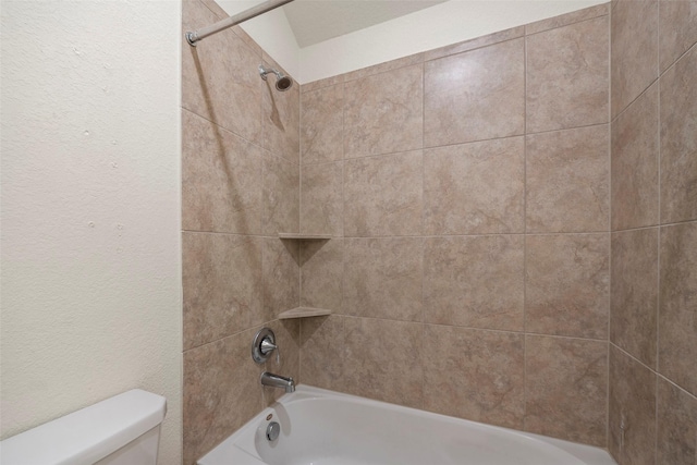 bathroom with tiled shower / bath combo and toilet