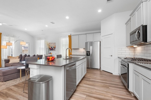 kitchen with sink, a breakfast bar area, light hardwood / wood-style flooring, stainless steel appliances, and a kitchen island with sink