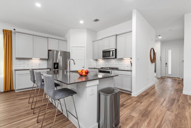 kitchen featuring sink, a breakfast bar area, light hardwood / wood-style flooring, a kitchen island with sink, and stainless steel appliances