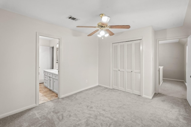 unfurnished bedroom featuring sink, ceiling fan, ensuite bathroom, light carpet, and a closet