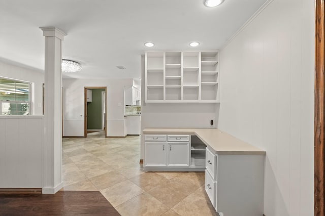 kitchen with white cabinetry, built in desk, and ornate columns