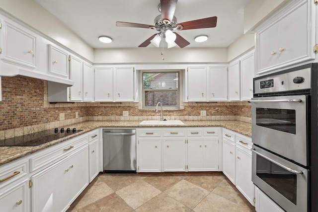 kitchen featuring sink, white cabinetry, backsplash, stainless steel appliances, and light stone counters