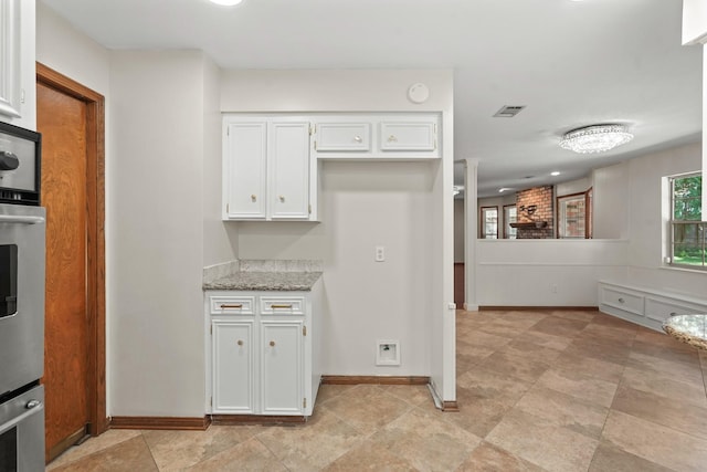 kitchen with white cabinetry and light stone countertops