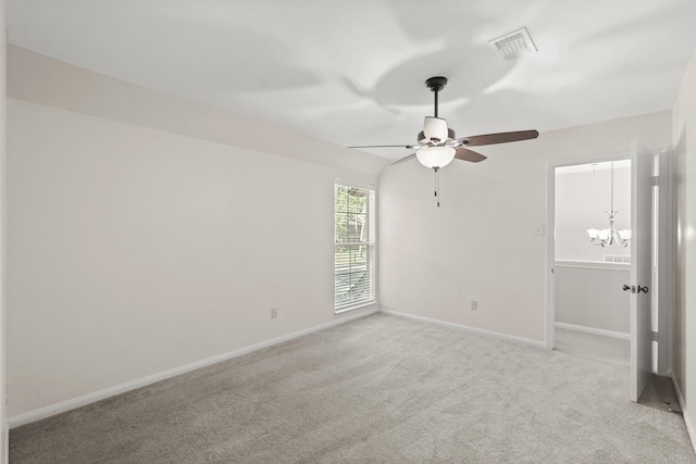 spare room with ceiling fan with notable chandelier and light colored carpet