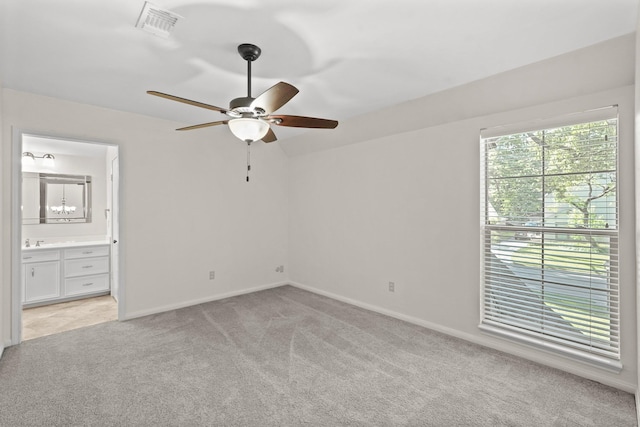 unfurnished bedroom with ensuite bathroom, sink, light carpet, and ceiling fan