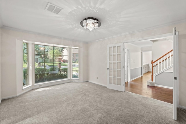 spare room with crown molding, carpet floors, french doors, and a chandelier