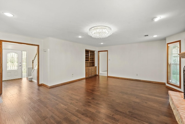 spare room with dark hardwood / wood-style floors and an inviting chandelier