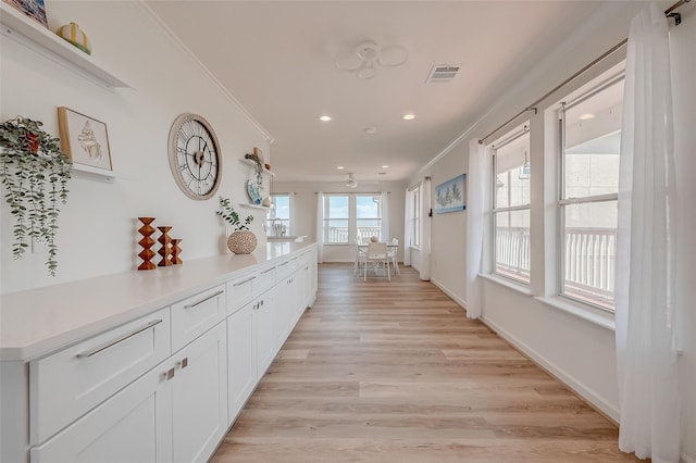 hall with ornamental molding and light hardwood / wood-style floors