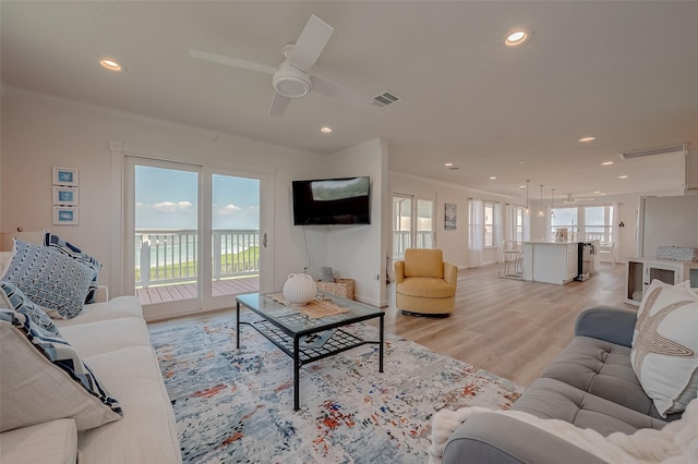 living room featuring crown molding, light hardwood / wood-style flooring, and ceiling fan