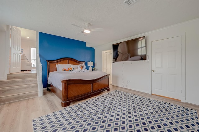 bedroom with crown molding, a textured ceiling, a closet, hardwood / wood-style flooring, and ceiling fan