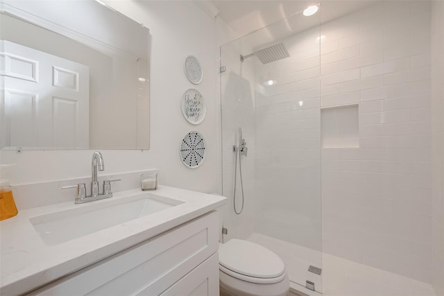 bathroom featuring a tile shower, vanity, and toilet