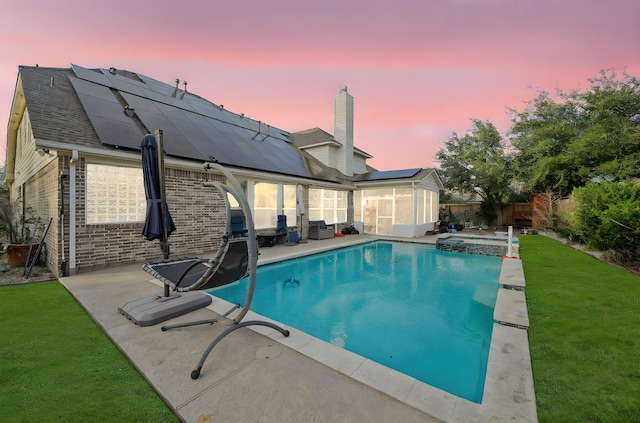 pool at dusk featuring a yard and a patio