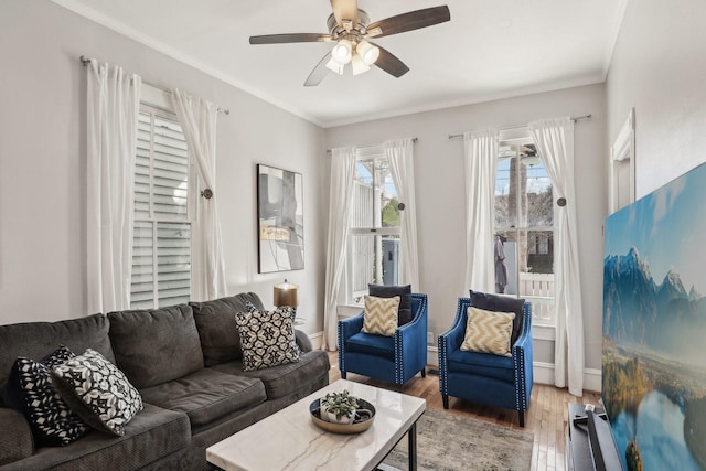 living area with light wood-style flooring, baseboards, and a ceiling fan