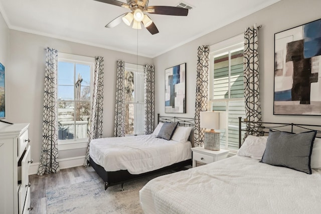 bedroom featuring baseboards, visible vents, ceiling fan, wood finished floors, and crown molding