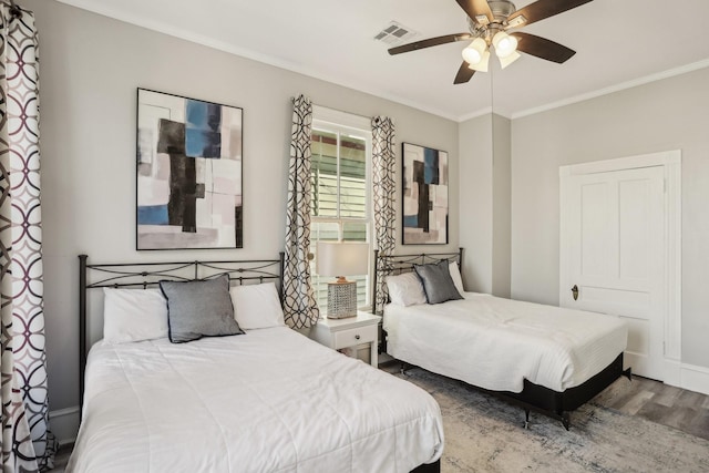 bedroom with baseboards, visible vents, a ceiling fan, ornamental molding, and wood finished floors