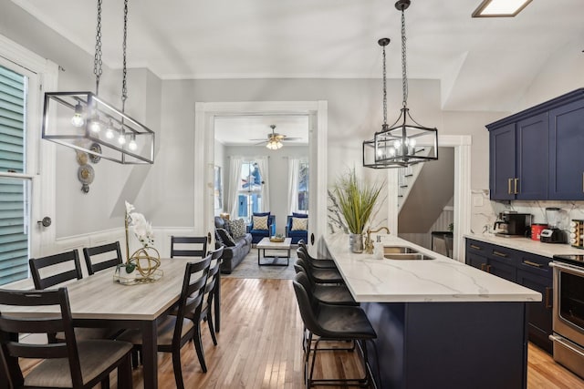 kitchen with stainless steel electric range oven, light wood-type flooring, a sink, and light stone countertops