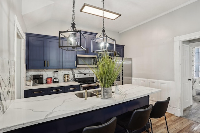 kitchen featuring blue cabinets, a kitchen breakfast bar, light wood-style floors, appliances with stainless steel finishes, and decorative light fixtures