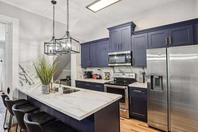 kitchen featuring light stone counters, stainless steel appliances, decorative backsplash, a sink, and a kitchen breakfast bar