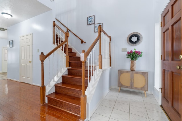 staircase with a high ceiling and hardwood / wood-style floors