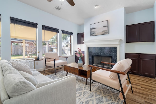 living room with ceiling fan, a fireplace, and light wood-type flooring