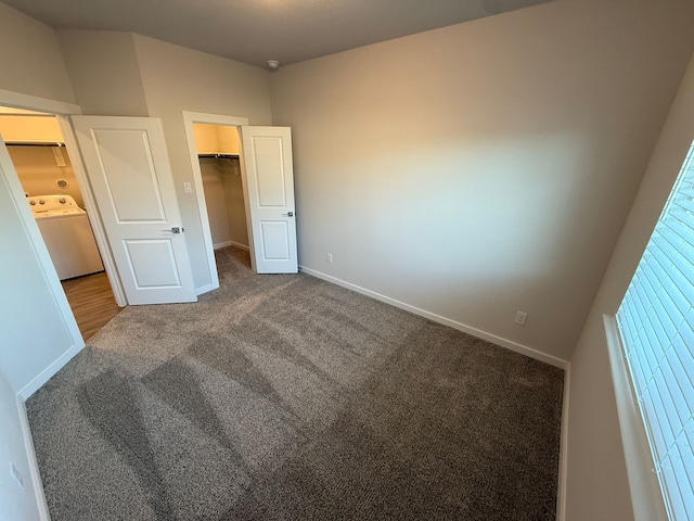 unfurnished bedroom with washer / clothes dryer, a walk in closet, carpet floors, and a closet