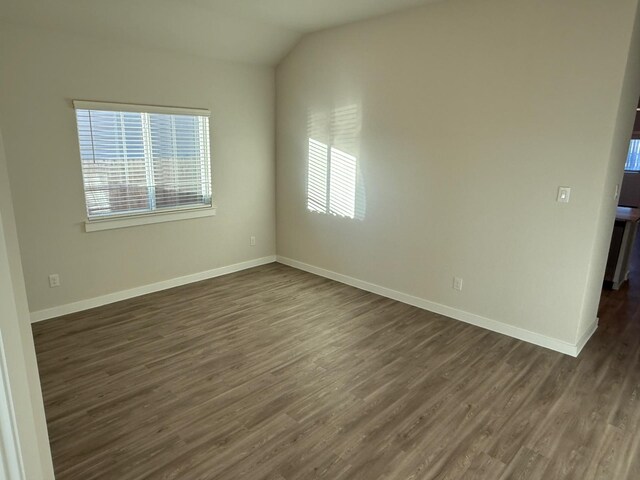 empty room featuring vaulted ceiling and dark wood-type flooring