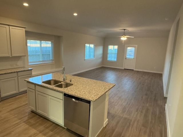 kitchen featuring sink, plenty of natural light, light stone counters, a center island with sink, and stainless steel dishwasher