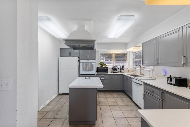 kitchen featuring sink, light tile patterned floors, gray cabinets, a kitchen island, and white appliances