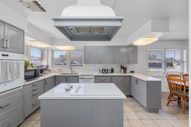 kitchen featuring a kitchen island, dishwasher, sink, gray cabinetry, and oven