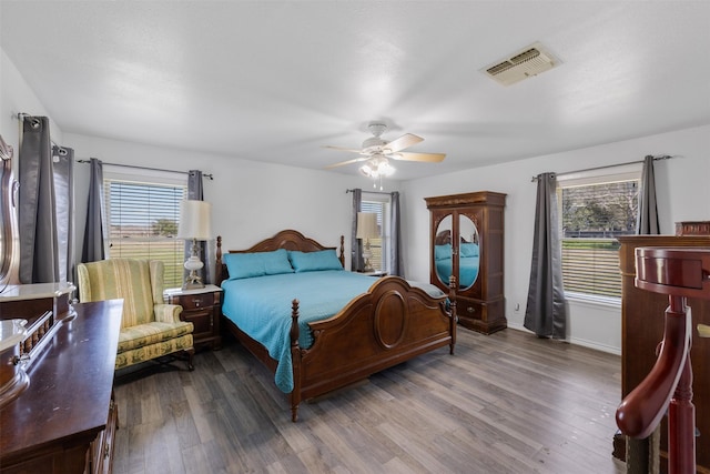 bedroom with multiple windows, dark hardwood / wood-style floors, and ceiling fan