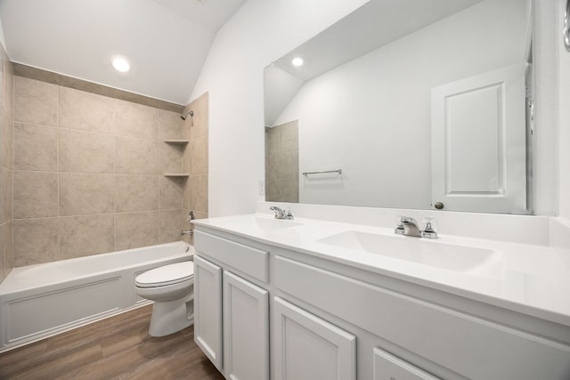 full bathroom with lofted ceiling, hardwood / wood-style flooring, vanity, toilet, and tiled shower / bath