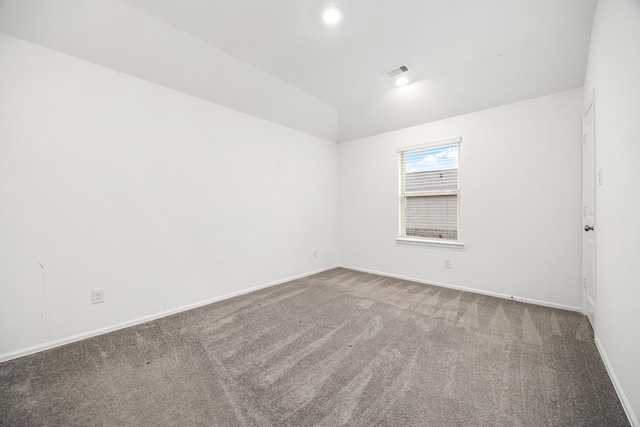 carpeted empty room featuring vaulted ceiling