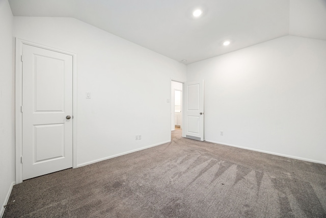 carpeted spare room with vaulted ceiling