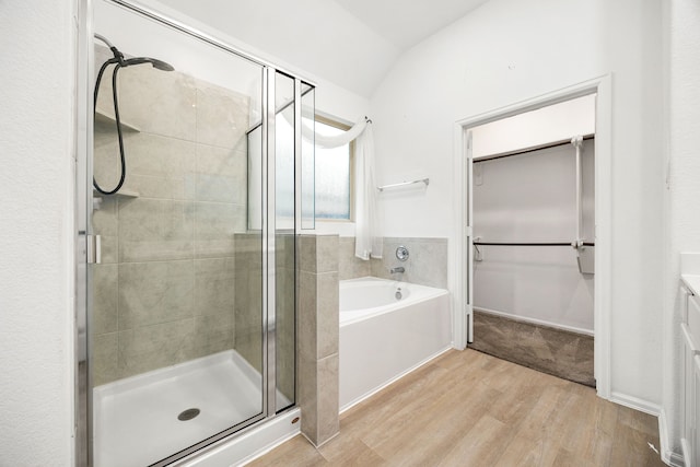 bathroom featuring vanity, wood-type flooring, independent shower and bath, and vaulted ceiling