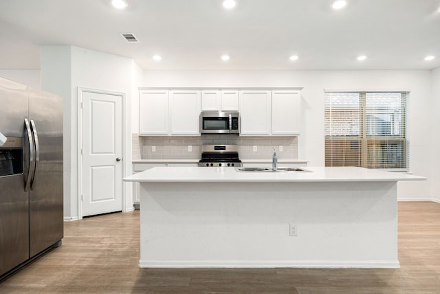 kitchen with sink, white cabinets, stainless steel appliances, a center island with sink, and light hardwood / wood-style flooring