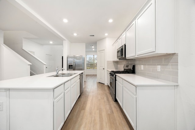 kitchen featuring stainless steel appliances, white cabinetry, sink, and a kitchen island with sink