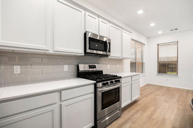 kitchen featuring stainless steel appliances, light hardwood / wood-style floors, decorative backsplash, and white cabinets