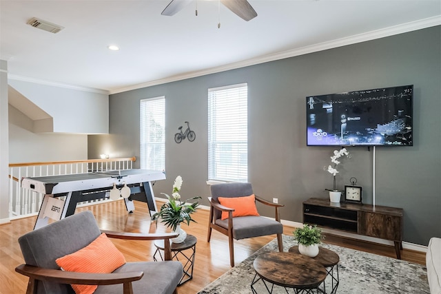 living area featuring light wood-type flooring, baseboards, visible vents, and crown molding