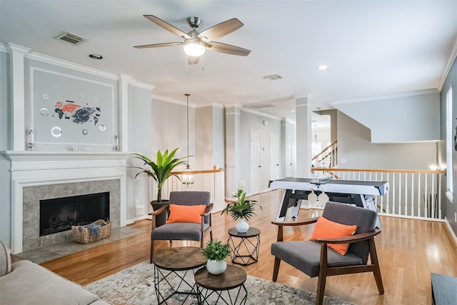 living room featuring light wood finished floors, visible vents, ornate columns, and ornamental molding